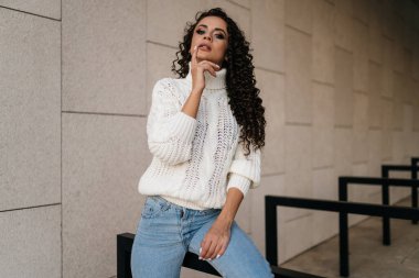 Kıvırcık güzellik gururla çenesini kaldırıyor ve dudaklarına dokunuyor.