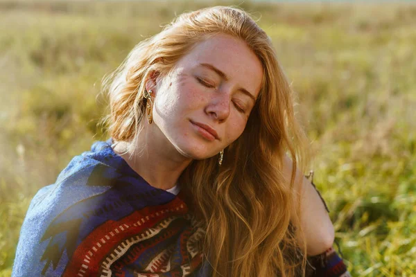 Chica acaricia su cabello con dicha cubriendo sus ojos sentados en la hierba — Foto de Stock