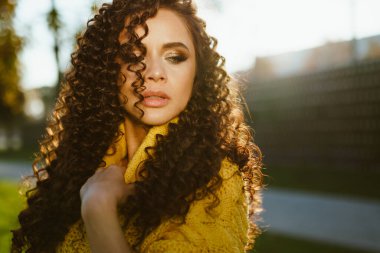 Kıvırcık esmer, süngerlerini açıyor ve parkta zaptedilemez bir bakışla gözlerini indiriyor.