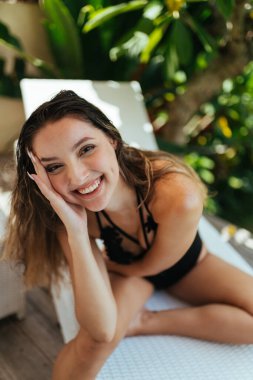 Shizong 'un üzerinde bir kız oturuyor ve neşeli bir şekilde gülüyor egzotik bir ağacın arka planında bir sıra pürüzsüz dişlerini göstererek