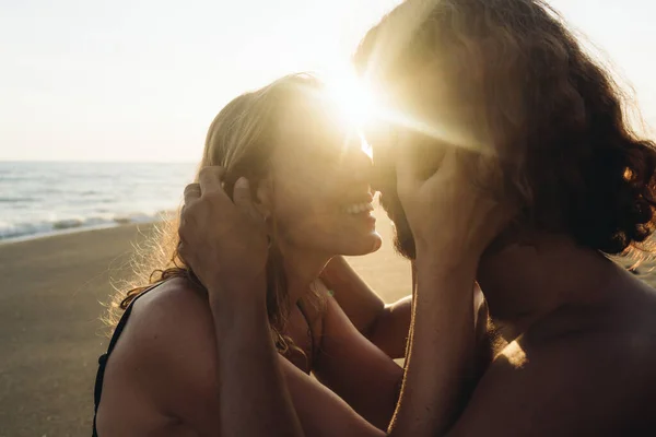 Regozija-se no encontro com sua amada menina abraçando a cabeça com as mãos e esfrega suavemente o nariz contra ele nos raios do pôr do sol. close-up — Fotografia de Stock