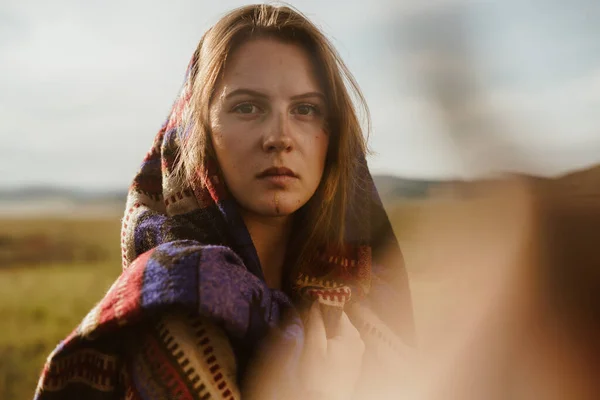 Primer plano. La chica, alarmada por la mirada de hermosos ojos sin maquillaje, mira a la distancia envuelta en una capa de etno — Foto de Stock