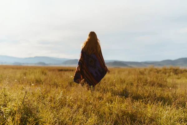 Envuelto en escocesa figura de una niña con el pelo largo extendido en la espalda se retira a lo largo de la estepa hacia las colinas — Foto de Stock