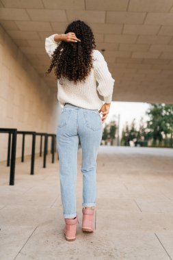 Kıvırcık saçlarını kafasının arkasına ayarlayan bir kız tünelden geçerek kameradan uzaklaşır.