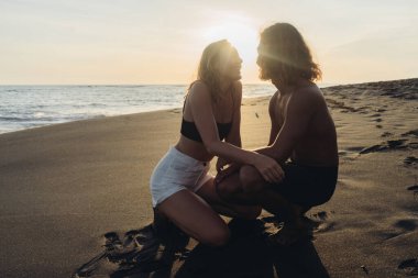 Gün batımında okyanusun kıyısındaki kumsalda birbirine hayran bir çift oturuyor.