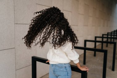 Havada uçuşan kıvırcık buklelerin etrafında keskin dönüşler yapan bir güzelliğin