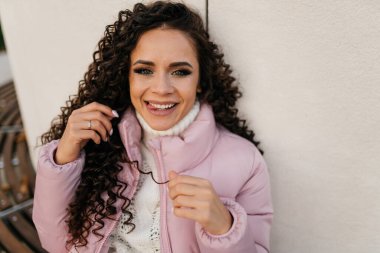 Kahkahalar ve yaramaz bakışlar, uzun kıvırcık saçlı dilin ucunu uzatan kız, birine sataşıyor.