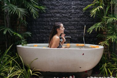 Su ve sarı çiçek tomurcuklarıyla dolu bir banyo açık havada durur ve bir kız spa ameliyatı olur.