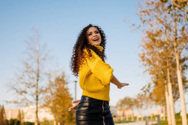 Parkta neşeyle gülümseyen kıvırcık, güzel esmer.