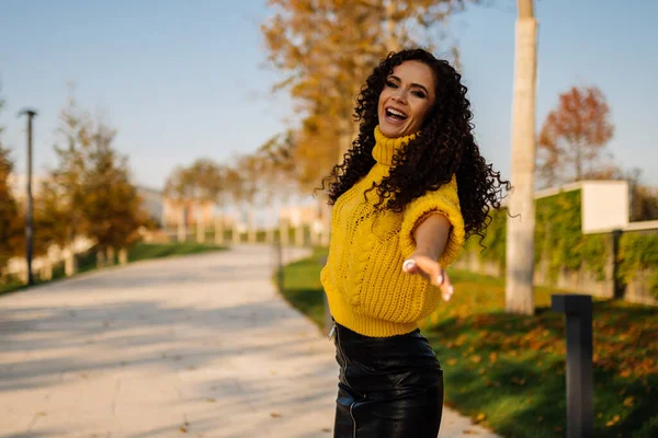 Parktaki pistte açık ağızlı, parlak bir kazak ve deri etekli kıvırcık esmer bir eli ileri koyarak şarkı söylüyor.