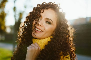 Yakın plan. Kıvırcık esmer, yeşil gözlü, büyüleyici gülümseyen.