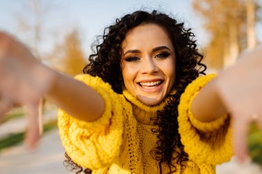 Kollarını ileri uzatıyordu. Parlak, kıvırcık esmer bir gülümseme, mutlu, beyaz dişli bir gülümseme.