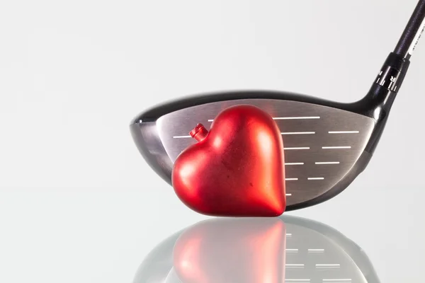 Club de golf y corazón rojo en una mesa de cristal — Foto de Stock