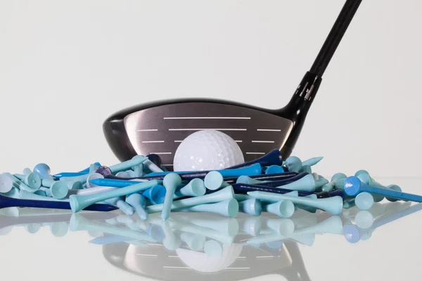 Golf driver and wooden tees on a glass desk