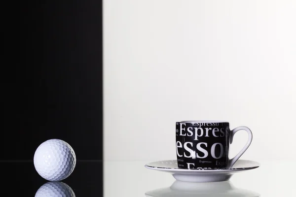 Schwarze Tasse Kaffee und weißer Golfball — Stockfoto