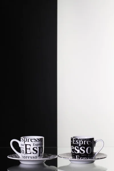 Tasses de café noir et blanc sur une table en verre — Photo