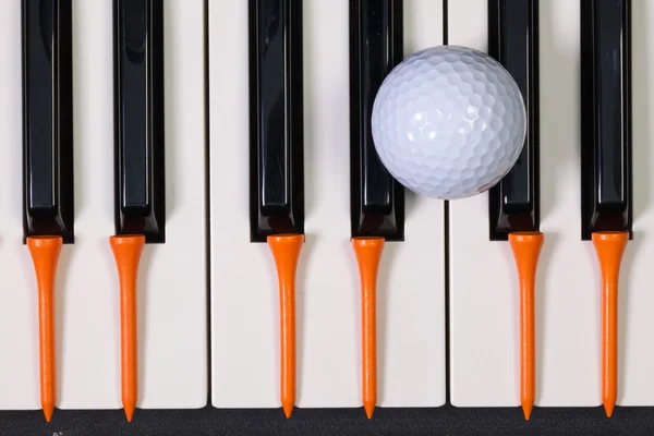 Teclado de piano y diferentes pelotas de golf y tees — Foto de Stock
