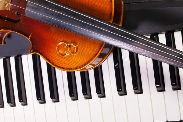 Piano keyboard, old violin and wedding rings — Stock Photo, Image