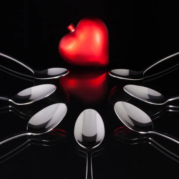 Teáskanál és szerelem szimbóluma a fekete üveg íróasztal — Stock Fotó