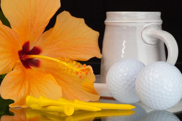 Fleur d'hibiscus orange, tasse de café et balles de golf — Photo