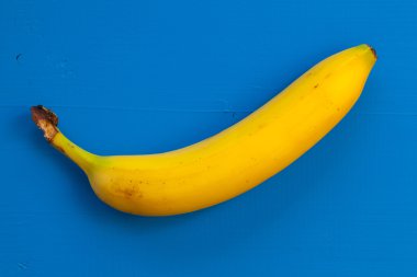 Tek muz mavi masanın üzerinde izole