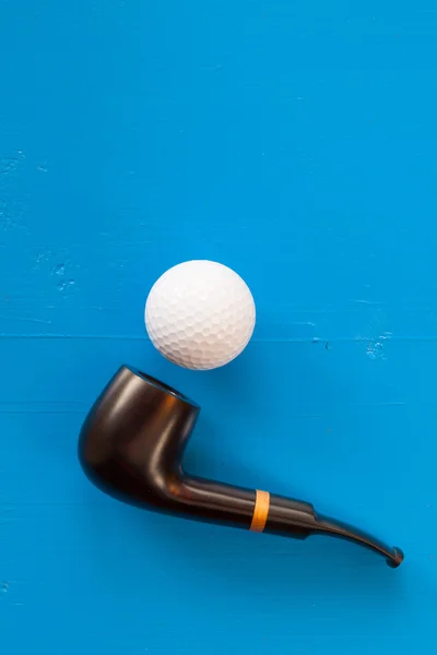 Tubulação de tabaco de luxo e bola de golfe na mesa azul — Fotografia de Stock