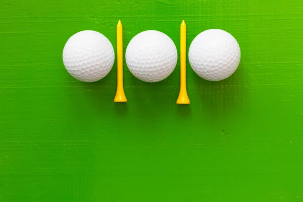 Bolas de golfe e camisetas de golfe de madeira na mesa verde — Fotografia de Stock