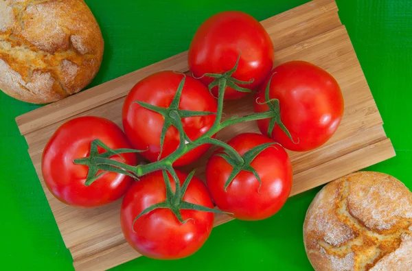 Colazione - Due pane di grano e pomodori rossi sul tavolo di legno — Foto Stock