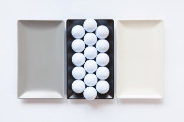 Beyaz adam üzerinde golf topları ile farklı seramik yemekler