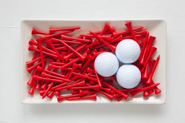 Pratos de cerâmica branca com bolas de golfe e tees de madeira — Fotografia de Stock