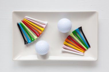 Golf topları ve ahşap tees ile beyaz seramik yemekleri 