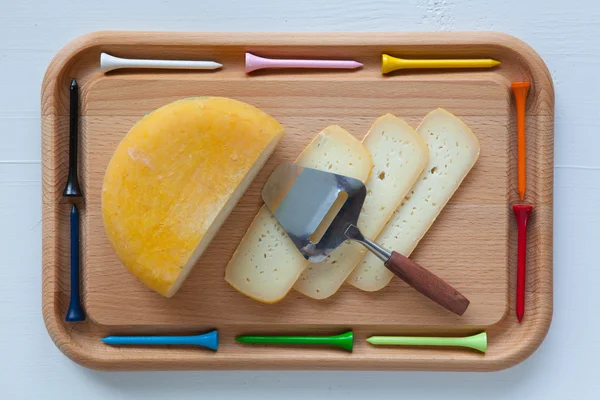 Blok smaczny ser na deska do krojenia z nożem i golf tee — Zdjęcie stockowe