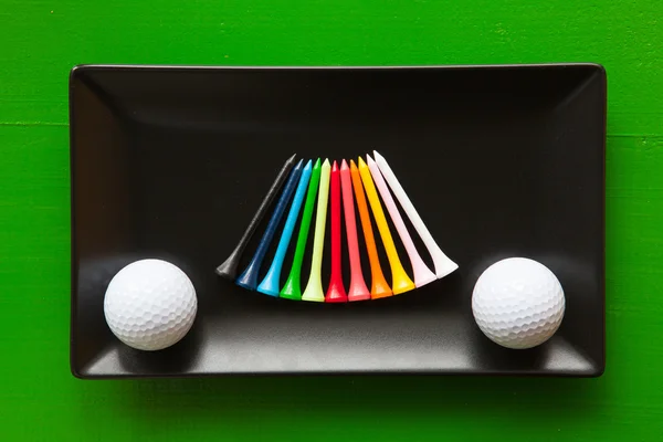 Pratos de cerâmica preta com bolas de golfe e tees de madeira — Fotografia de Stock