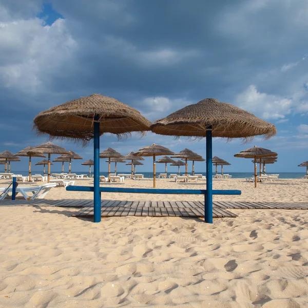 Különböző napernyőkkel és napozóágyakkal, tavira üres strandon — Stock Fotó