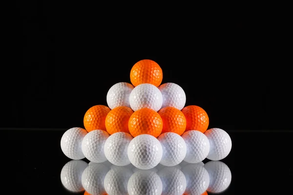 Pyramid av golfbollar på svart bakgrund — Stockfoto