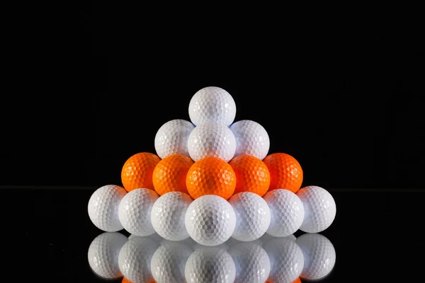 Pirâmide de bolas de golfe em um fundo preto — Fotografia de Stock