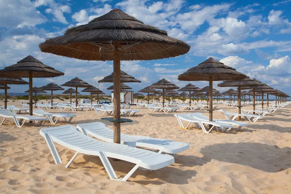 Különböző napernyőkkel és napozóágyakkal, tavira üres strandon — Stock Fotó