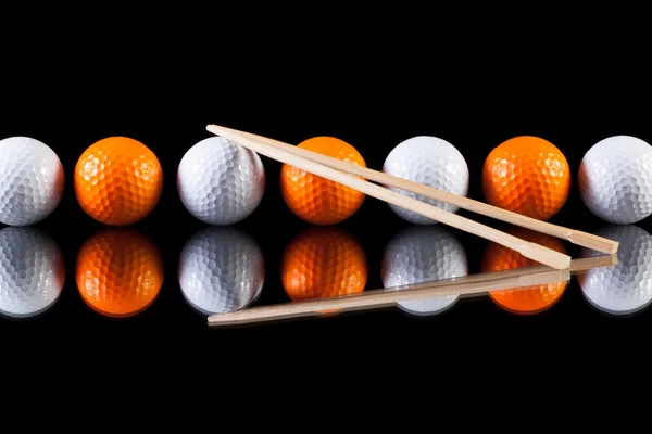 Palle da golf bianche e arancioni con bacchette di bambù sul vetro — Foto Stock