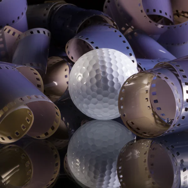 Close-up of a roll 35 mm photographic films and golf ball — Stock Photo, Image