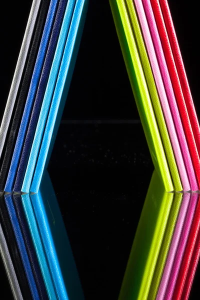 Zwölf farbige Tagebücher auf einem gläsernen Schreibtisch — Stockfoto