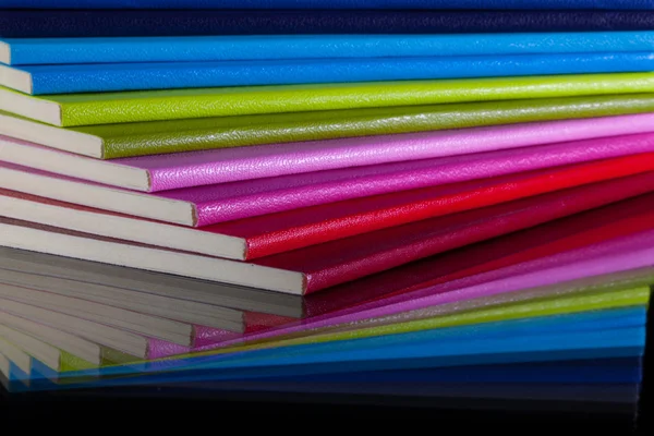 Twaalf verschillende kleuren dagboeken op een glas Bureau — Stockfoto