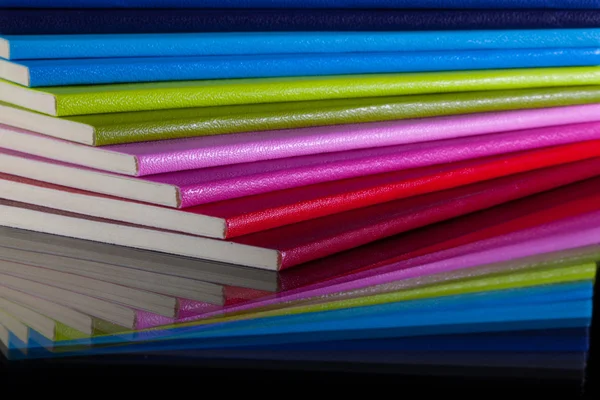 Doce diarios de colores diferentes en un escritorio de cristal — Foto de Stock