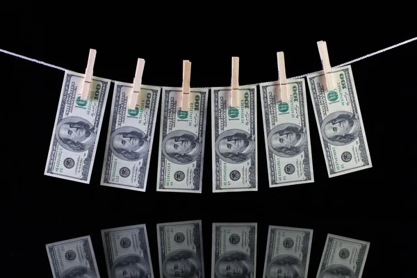Billetes sucios en dólares estadounidenses que cuelgan de un tendedero y reflejan —  Fotos de Stock
