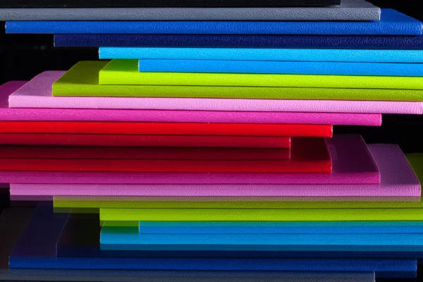 Douze journaux de couleurs différentes sur un bureau en verre — Photo