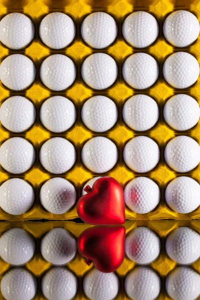 Golfballen in vak voor eieren en rood hart — Stockfoto