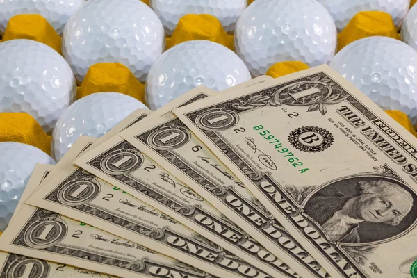 White golf balls in the yellow box and US money — Stock Photo, Image