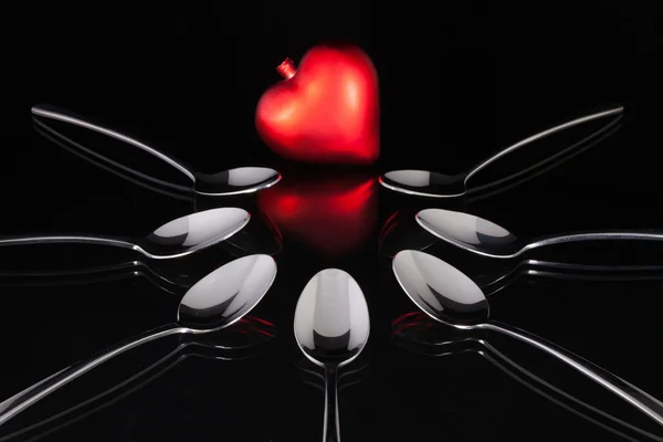 Cucharaditas y símbolo de amor en el escritorio de cristal negro —  Fotos de Stock