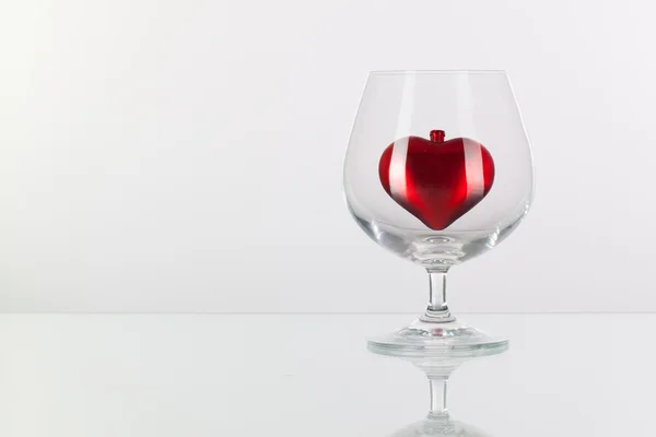 Red heart inside a glass of cognac — Stock Photo, Image