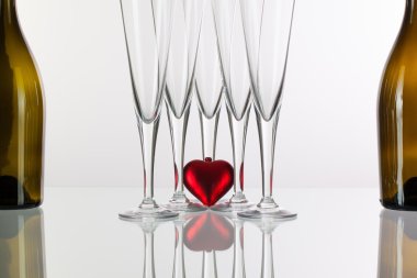 Beş şampanya bardağı ve cam masa üzerinde kırmızı kalp