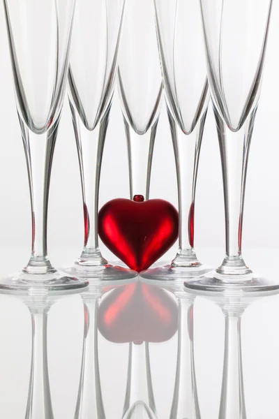 Cinq verres à champagne et coeur rouge sur un bureau en verre — Photo